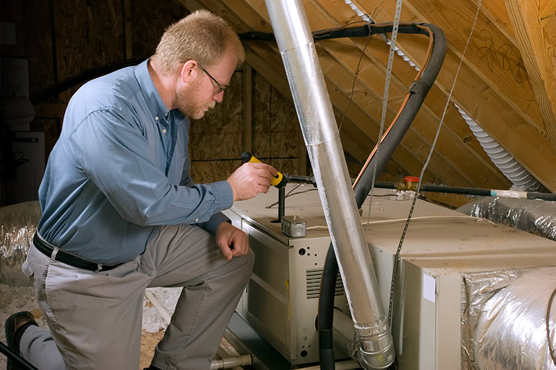 HVAC technician looking at furnace in attic of Farmington, Missouri, home.