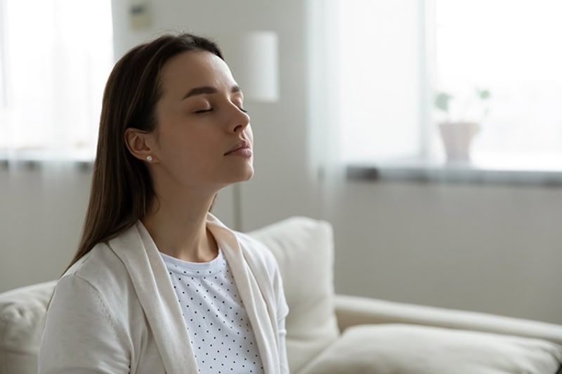 Female homeowner breathing in her home's indoor air after a visit from Crystal Heating & Cooling.